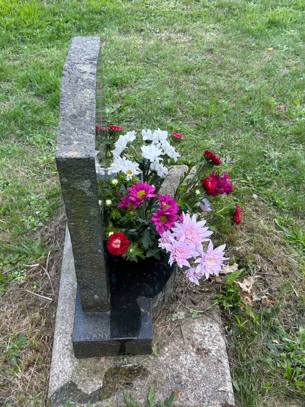 Pink, white and red flowers in the vase of a granite memorial, seen from the side