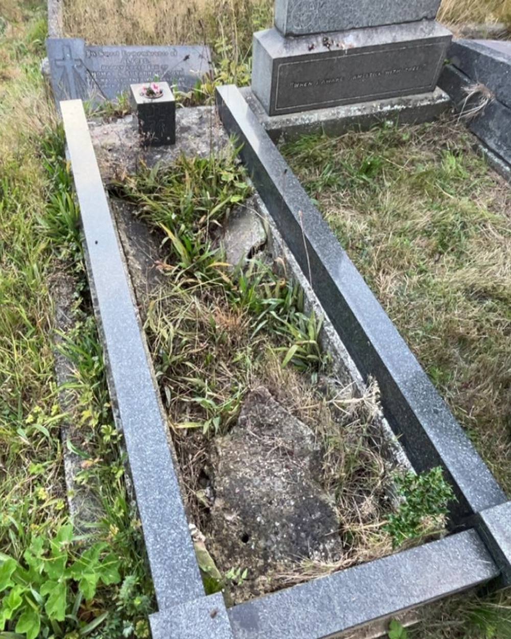 A kerbed grave overgrown with weeds and grass before a visit